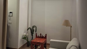 Een kamer met plafondventilator, een klein tafeltje met een vaas, een bank en een lamp.