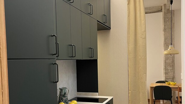 Een moderne keuken met grijze kastjes, een zwart aanrecht en een gele kom.
