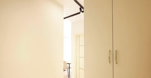 Ein Flur mit einer Tür zu einem Zimmer, einem Stuhl und einem Tisch im Hintergrund.