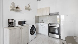 Una cucina compatta con lavatrice, forno a microonde, forno e macchina del caffè.
