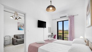 Camera d'albergo con un letto, una TV, una scrivania, una sedia e un balcone con vista.