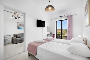 Habitación de hotel con cama, televisión, escritorio, silla y balcón con vistas.