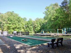A park with a green lawn, a playground, and a bench.