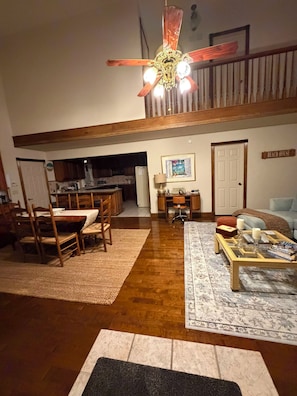 A spacious living area with a dining table, chairs, a coffee table, and a staircase leading to an upper level.