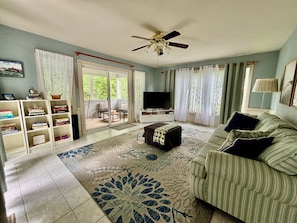 A living room with a sofa, a television, a bookshelf, and a ceiling fan. - Anchor Down by the Bay,  A Restful Retreat   in Lewes (Lewes)