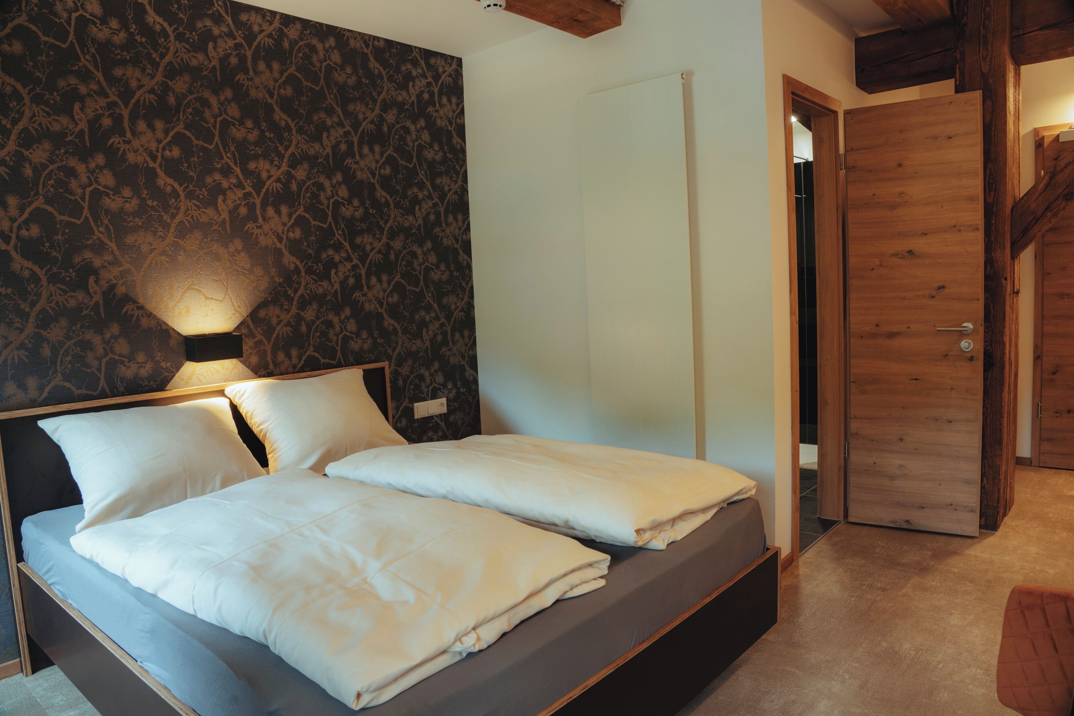 Una camera da letto con un letto, un comodino, una lampada e una porta in legno.