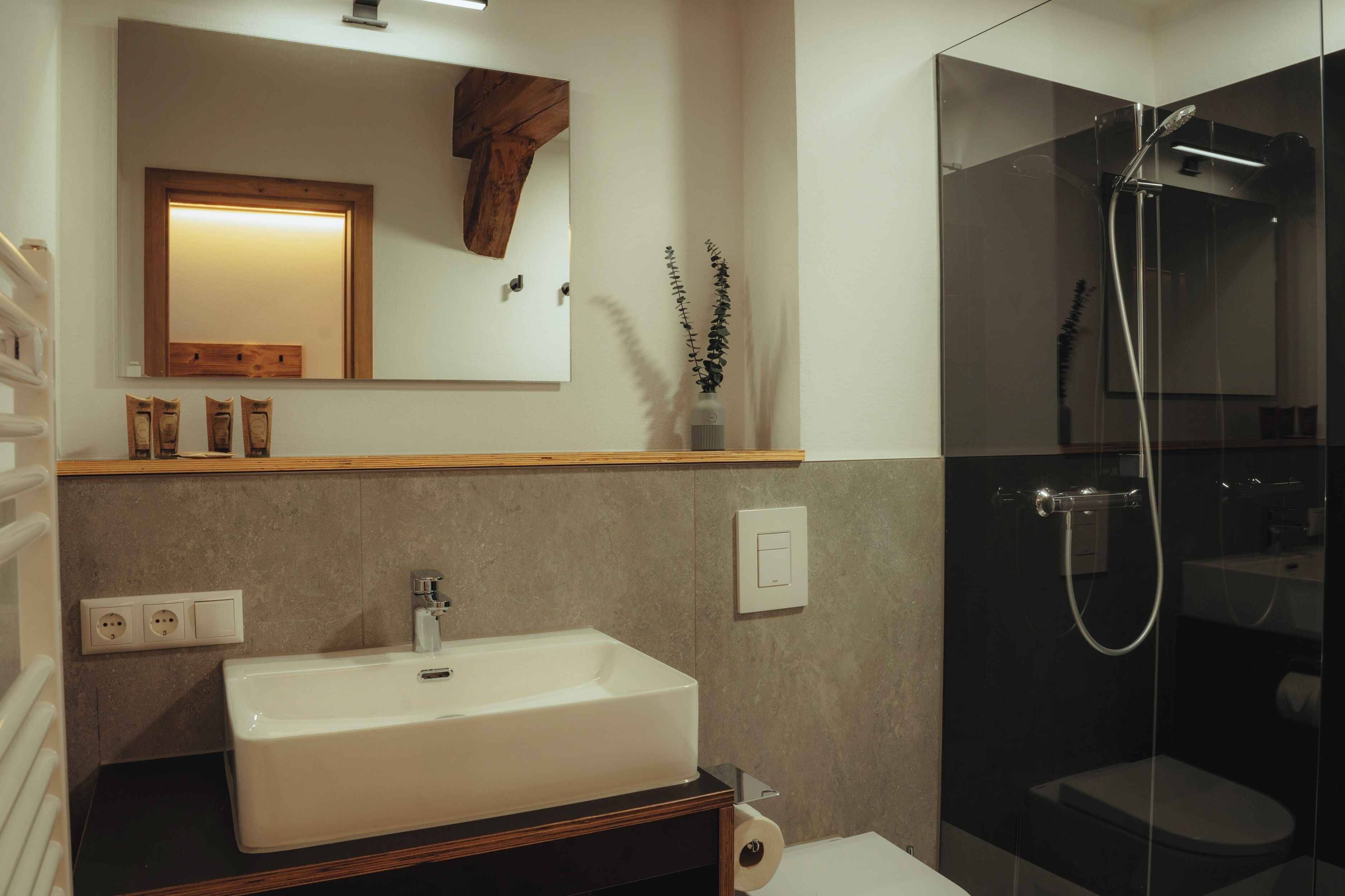 Een moderne badkamer met een grote wastafel, spiegel en douche.