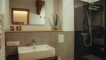 Een moderne badkamer met een grote wastafel, spiegel en douche.