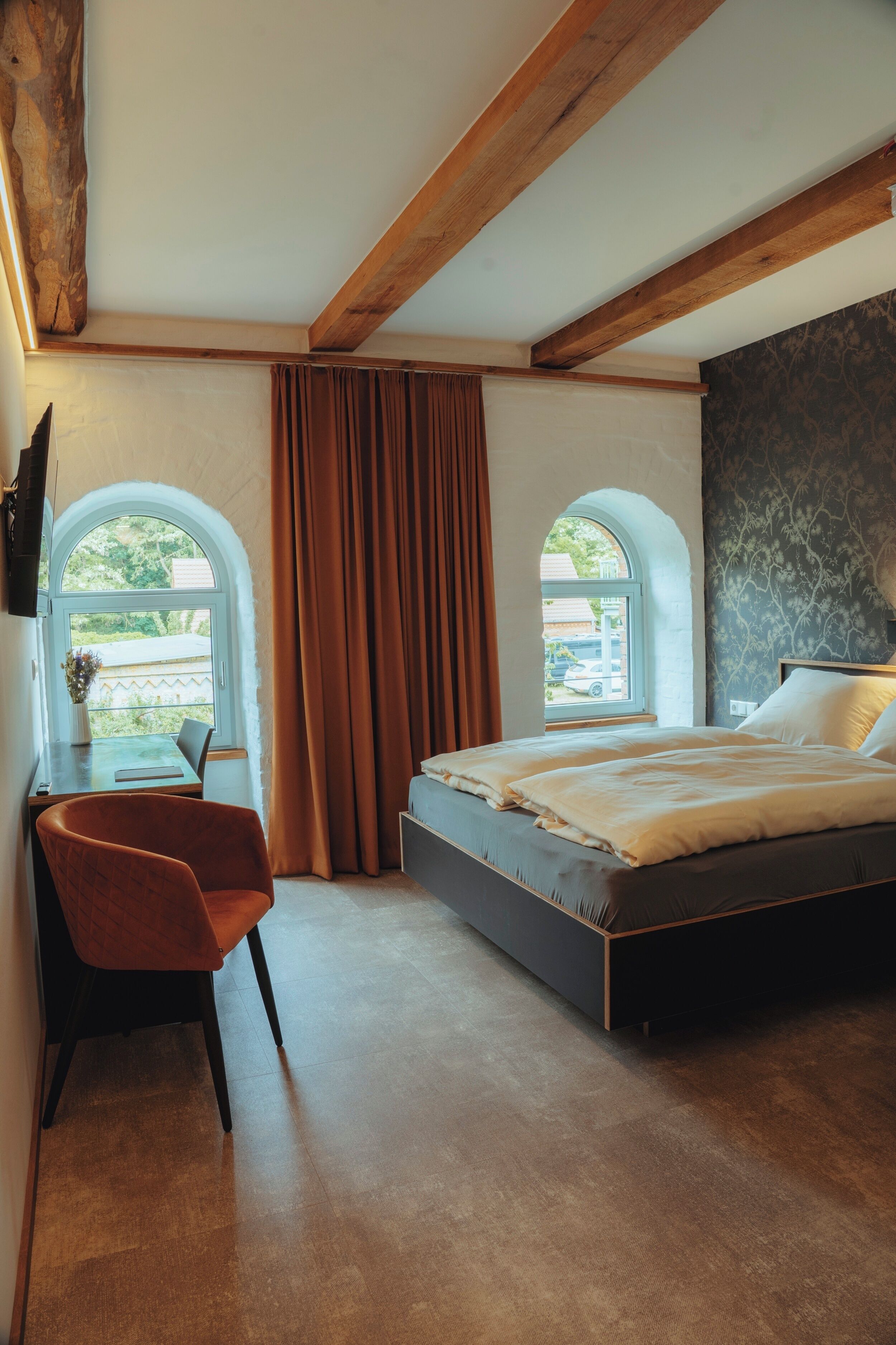 A bedroom with a bed, a chair, a window, and a view of the outside.