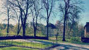 A cobblestone pathway leading through a park with bare trees and a distant building.