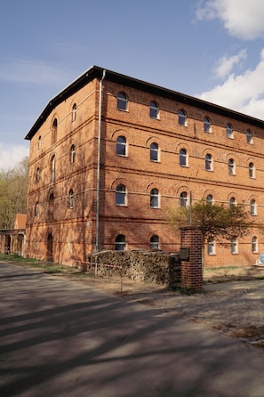 Un edificio de varios pisos de ladrillo con ventanas arqueadas y un muro de piedra al frente.