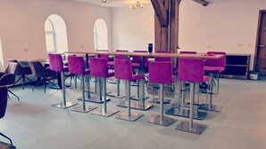 A conference room with a long table, purple chairs, and a wooden ceiling beam.