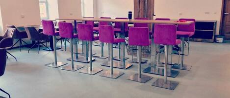 Une salle de conférence avec une longue table, des chaises violettes et une poutre en bois au plafond.