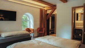 A bedroom with two beds, a TV, a wooden ceiling, and a window.