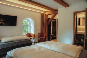 A bedroom with two beds, a TV, a wooden ceiling, and a window.