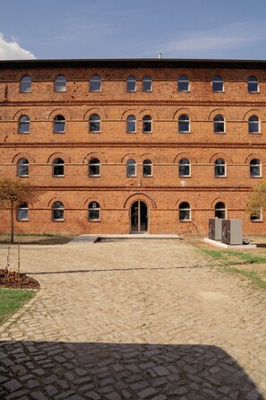 A large brick building with multiple windows and a central entrance. - Motel Q Kornspeicher (Neuruppin)