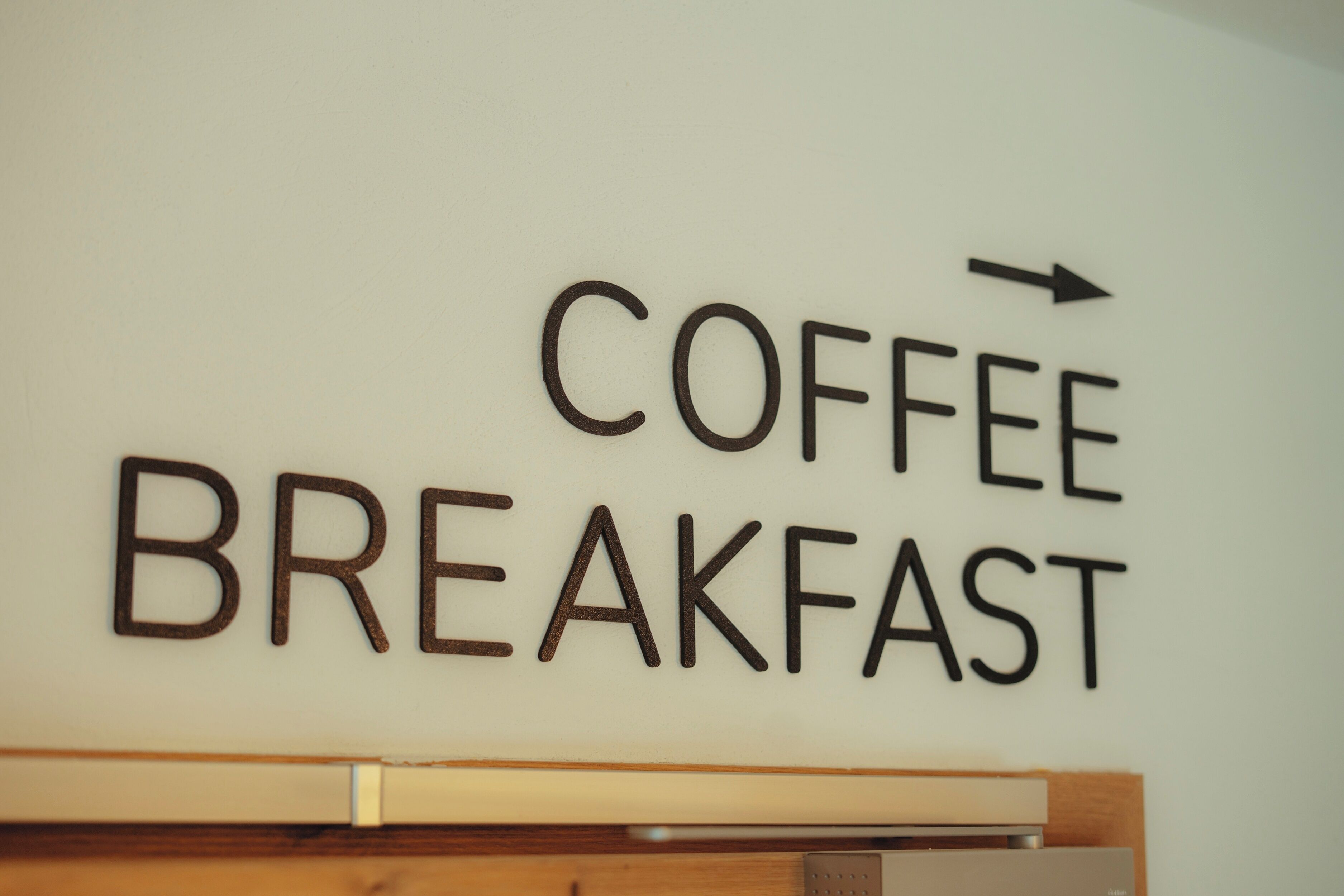 A wall sign with the words 'COFFEE BREAKFAST' and an arrow pointing to the right.