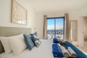 A hotel room with a bed, pillows, a view of the sea, and a balcony with a table and chairs. - Villa Kalandraka Pool, Sea Views, 10 min to Marina (Playa Blanca)