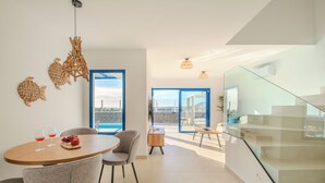 Et moderne interiør med spiseplads, trappe og udsigt gennem en glasdør.