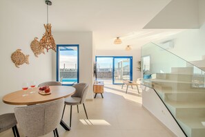 Ein modernes Interieur mit Essbereich, einer Treppe und Blick durch eine Glastür.