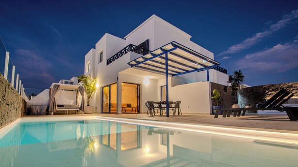 Et moderne hus med swimmingpool, udendørs møbler og en overdækket terrasse.