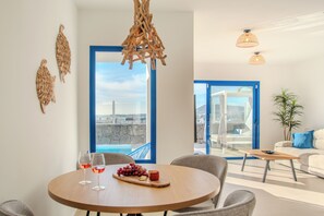 Ein modernes Wohnzimmer mit Essbereich, großen Fenstern und Meerblick.