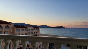 Un hôtel situé sur la côte, doté de balcons avec vue sur la mer, d’un espace piscine et offrant une vue sur une île au loin.