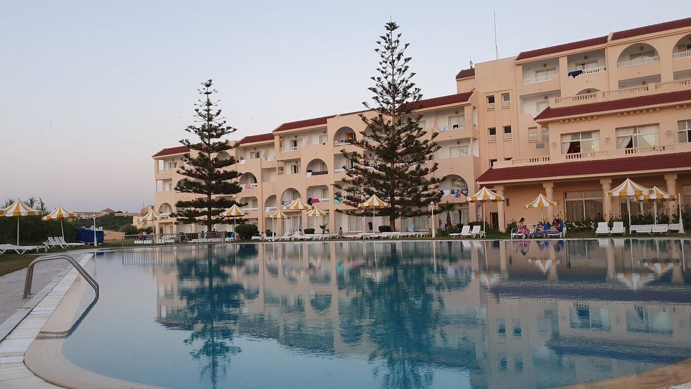 A hotel with a swimming pool, multiple balconies, and outdoor seating areas.
