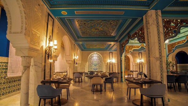 Une salle à manger luxueuse avec un sol en marbre, un plafond décoré et de magnifiques lustres.