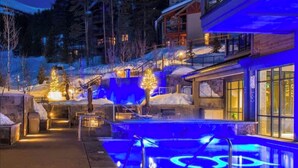 Un complexe hôtelier doté d’une piscine, entouré d’un paysage enneigé et d’arbres illuminés.