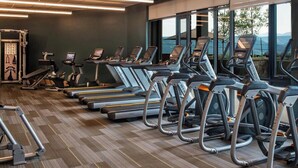 Une salle de sport équipée de tapis de course et d’appareils d’exercice, dotée de grandes fenêtres et offrant une vue sur l’extérieur.