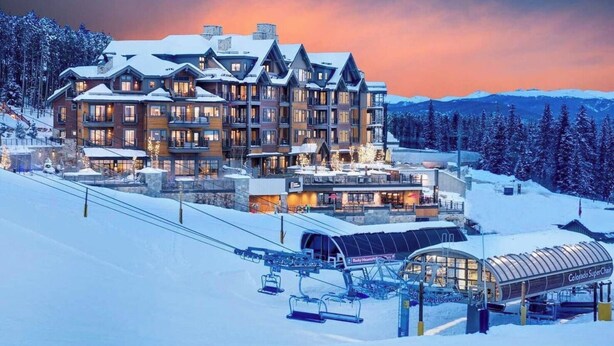 Un chalet à plusieurs étages doté d'un télésiège et entouré d'un paysage enneigé.