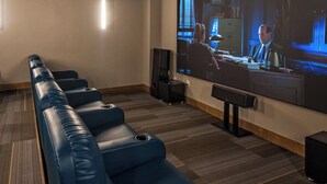 Une salle de cinéma privée avec des fauteuils en cuir inclinables, un grand écran et un plancher en bois.