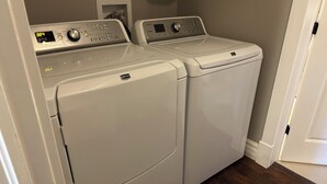 Deux machines à laver à chargement frontal dans une buanderie, le sol étant recouvert de parquet.