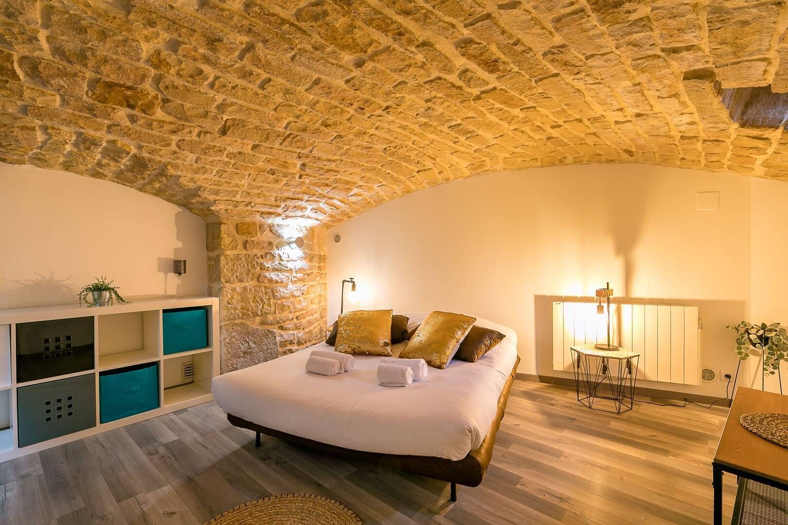 Une chambre avec un plafond en pierre, un lit avec des oreillers, une table de chevet, une lampe et une plante.