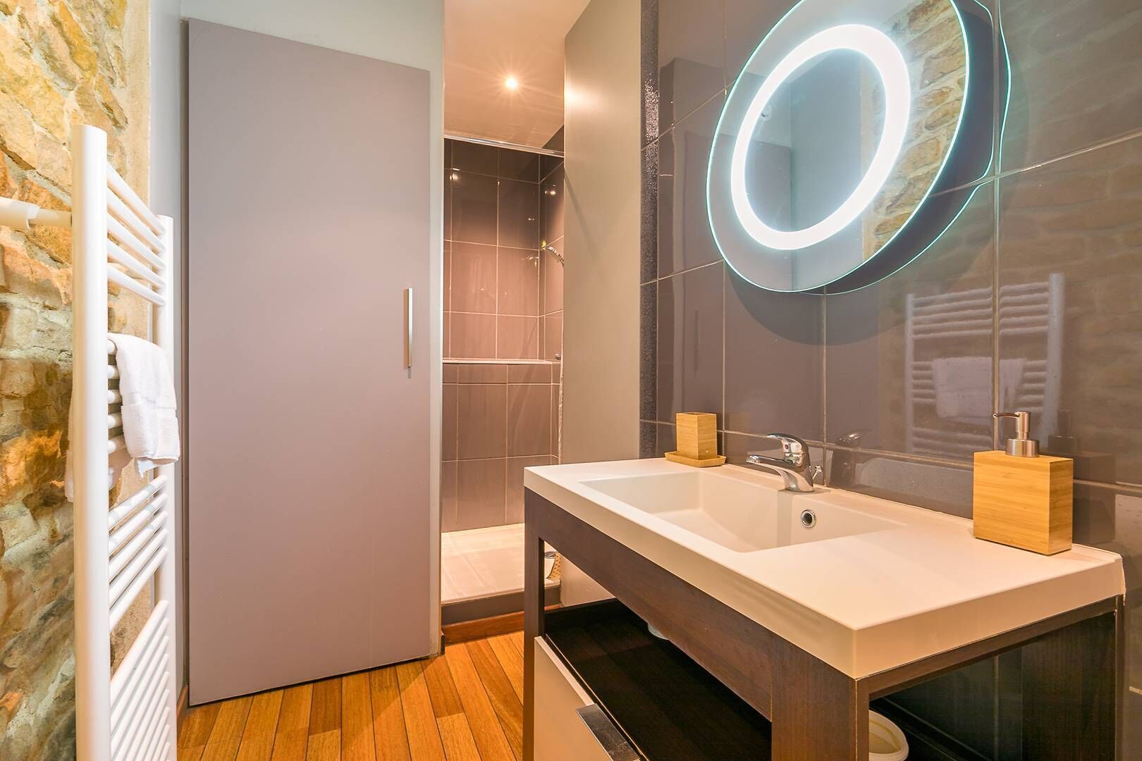 Une salle de bain moderne avec un grand miroir, un lavabo et une douche.