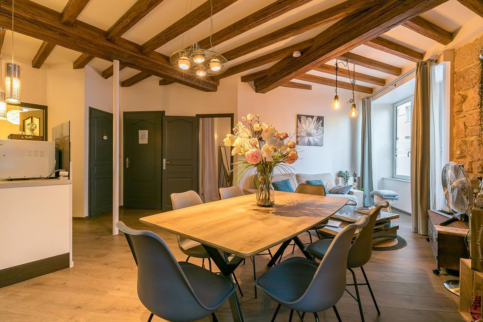 Un coin repas avec une table en bois, des chaises et un vase de fleurs.