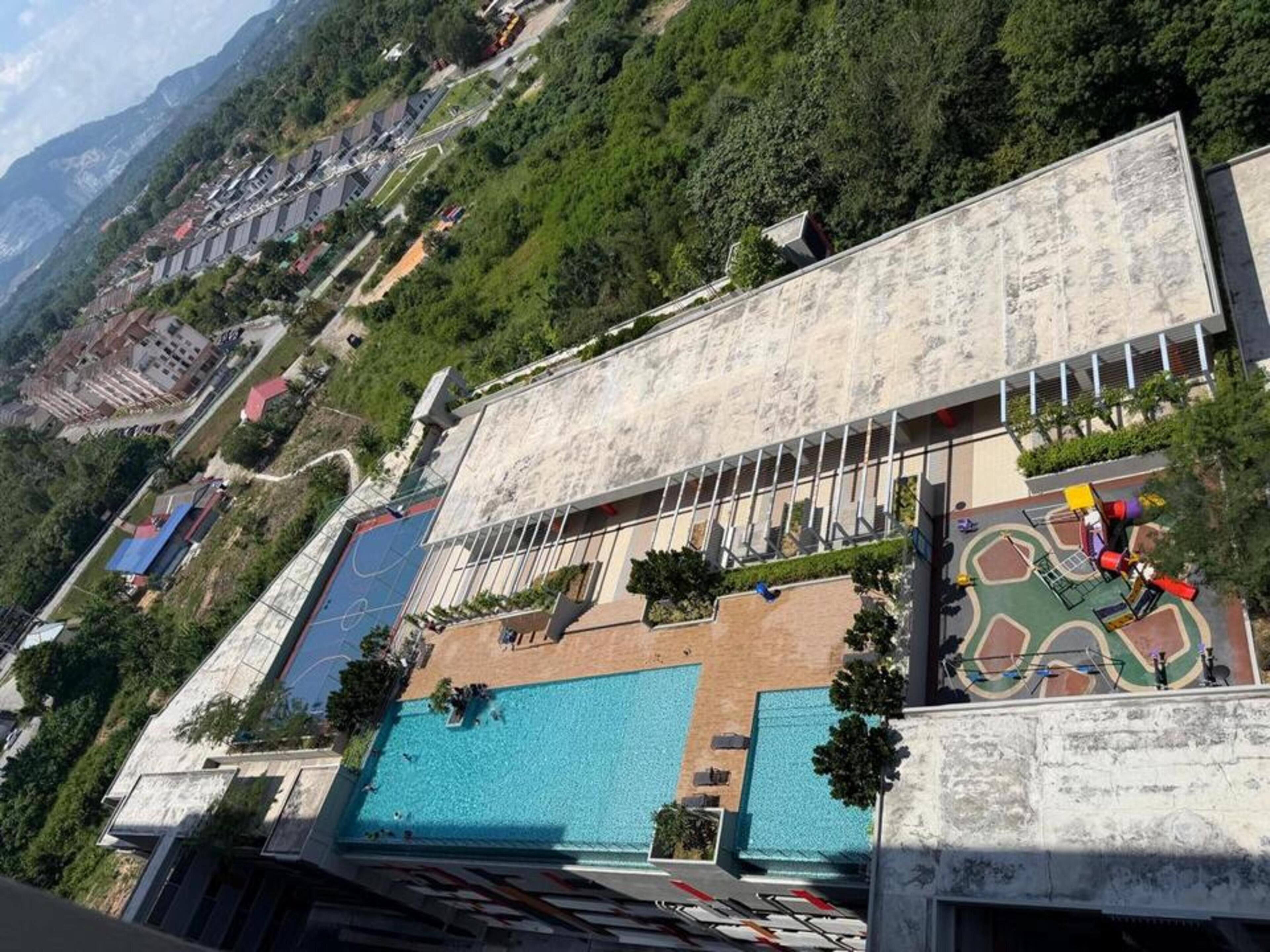 A hotel with a rooftop pool, a children's play area, and a view of the surrounding hills.