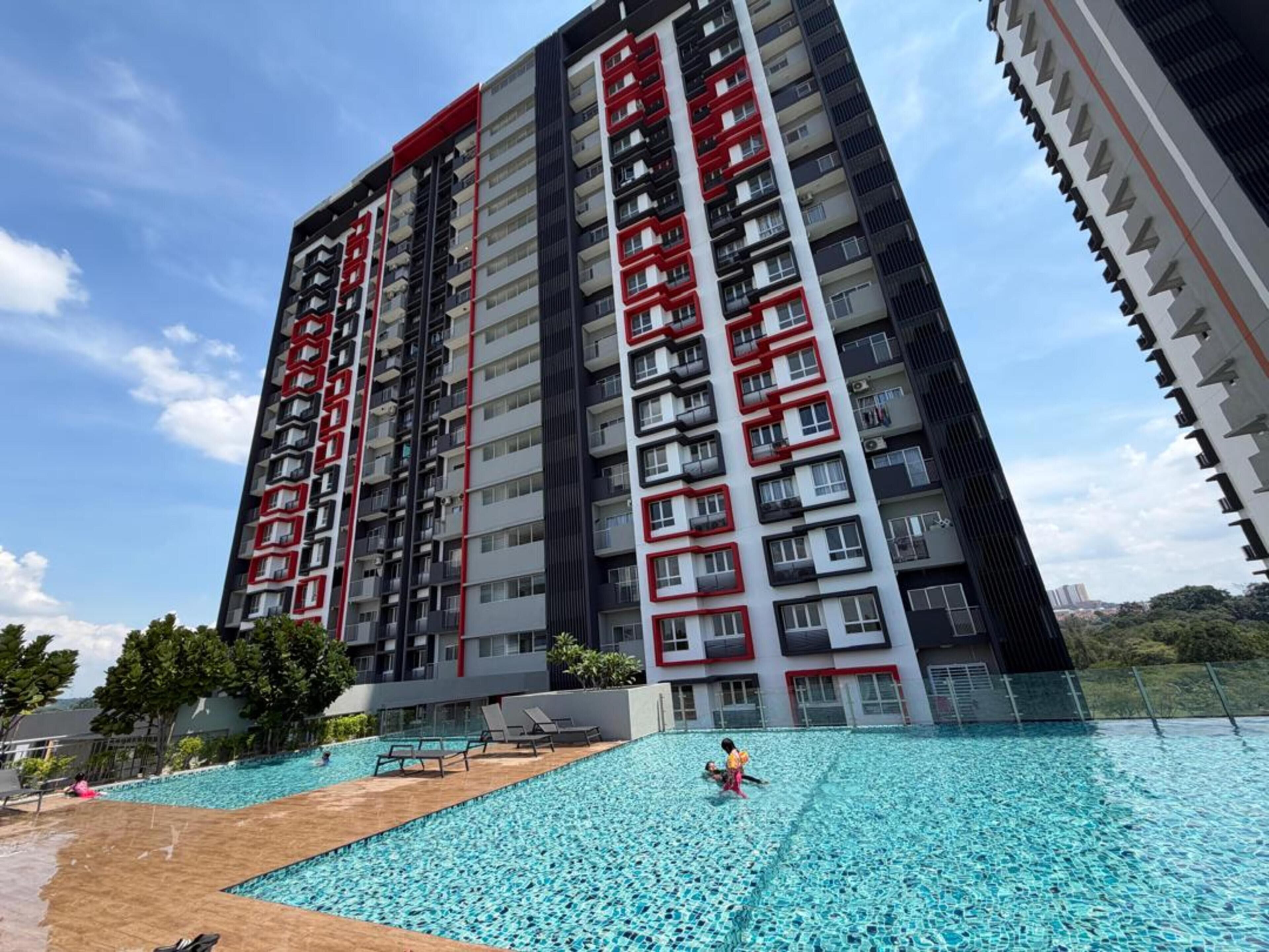 Un immeuble résidentiel de grande hauteur doté de nombreux balcons, d’une piscine et surplombant un ciel dégagé.