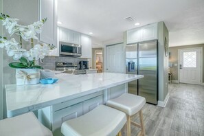 Eine moderne Küche mit Marmorarbeitsplatte, Edelstahlgeräten und einem großen Kühlschrank.