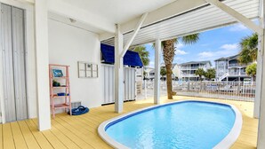 Et poolområde med træterrasse, stige og hvid gelænder.