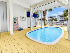 Ein Poolbereich mit Holzterrasse, einer Leiter und einem weißen Geländer.