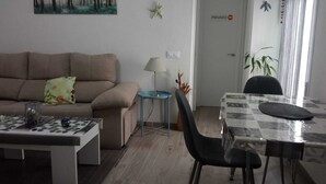 A living room with a sofa, a coffee table, a lamp, a dining table with chairs, and a painting on the wall. - Casa Marconi de Conil (Conil de la Frontera)