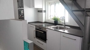 Eine moderne Küche mit weißen Schränken, einer Edelstahl-Spüle und einem eingebauten Backofen.