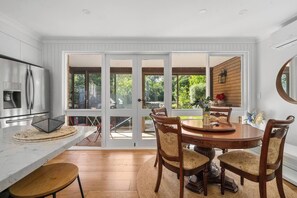 A modern kitchen with a dining area, large windows, and a view of the outdoors. - Warrina Retreat Parkside Serenity near Urban Life (Chatswood West)