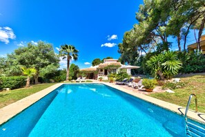 A swimming pool with lounge chairs, surrounded by greenery and a building with a tiled roof. - Casa Violeta — Mediterranean Art Villa in Jávea (Xàbia)