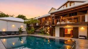 A modern house with a swimming pool, a covered outdoor area, and a staircase leading to a second floor. - NAYA (Saint-Martin)