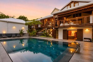 A modern house with a swimming pool, a covered outdoor area, and a staircase leading to a second floor. - NAYA (Saint-Martin)