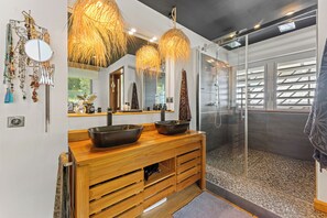 Ein modernes Badezimmer mit einem Holzkosmetikschrank, einem großen Spiegel und einer Glasdusche.