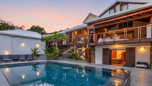 A modern house with a swimming pool, a covered outdoor area, and a staircase leading to a second floor. - NAYA (Saint-Martin)